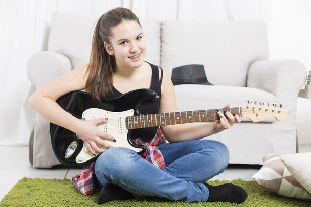 Teenager girl singer with guitar sitting on a floor  - Photo, Image