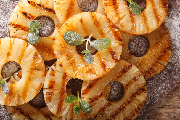 grilled pineapple with mint and powdered sugar close-up on the t - Foto, afbeelding