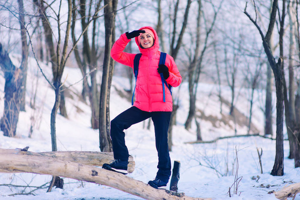 Mujer excursionista caminando sobre nieve Invierno bosque pendiente con mochila
 - Foto, imagen
