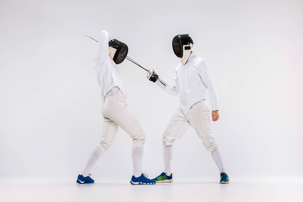 The two men wearing fencing suit practicing with sword against gray - Foto, immagini
