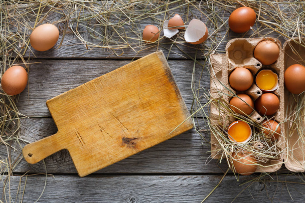 Verse bruine eieren in karton op rustieke houten achtergrond - Foto, afbeelding