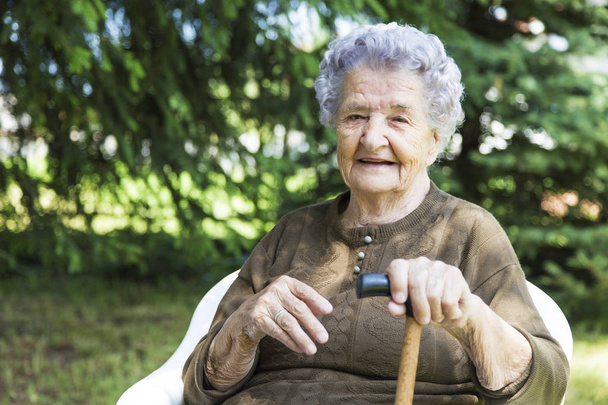 happy elderly woman sitting in garden - Foto, imagen