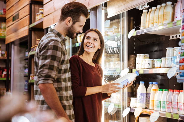 Couple talking and buying milk at grocery shop - Φωτογραφία, εικόνα