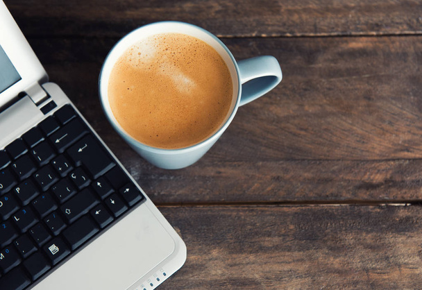 taza de café junto a un pequeño ordenador
 - Foto, imagen