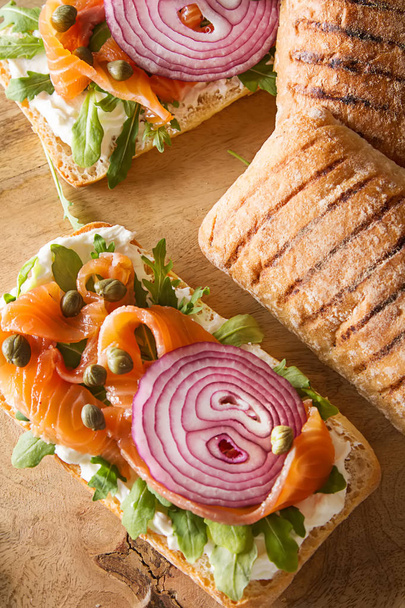 homemade baguette with smoked salmon, onions and arugula. Wooden - Фото, зображення