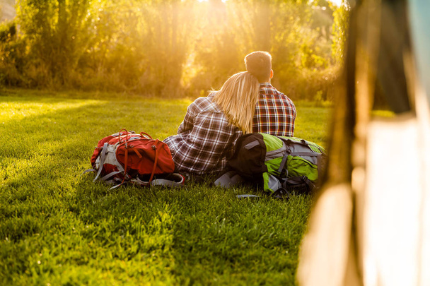couple with backpacks sitting on grass - Fotoğraf, Görsel