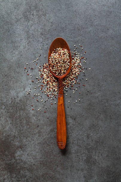 Quinoa in a wooden spoon on a dark background - Фото, изображение
