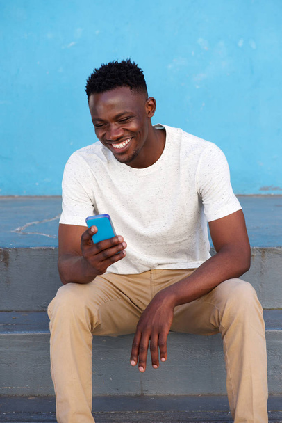 африканский человек сидит и пользуется телефоном
 - Фото, изображение