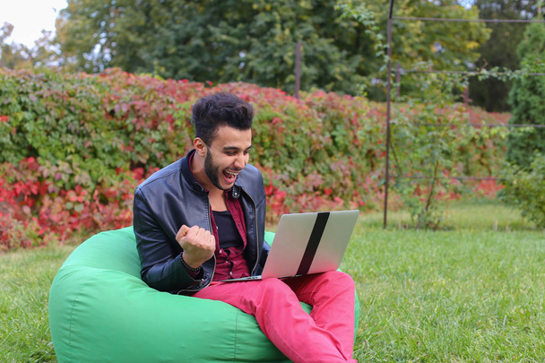 Le jeune homme d'affaires arabe réussi s'assoit avec l'ordinateur portable dans la chaise, S
 - Photo, image