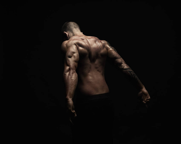 Unrecognizable man shows strong back muscles closeup - Foto, afbeelding