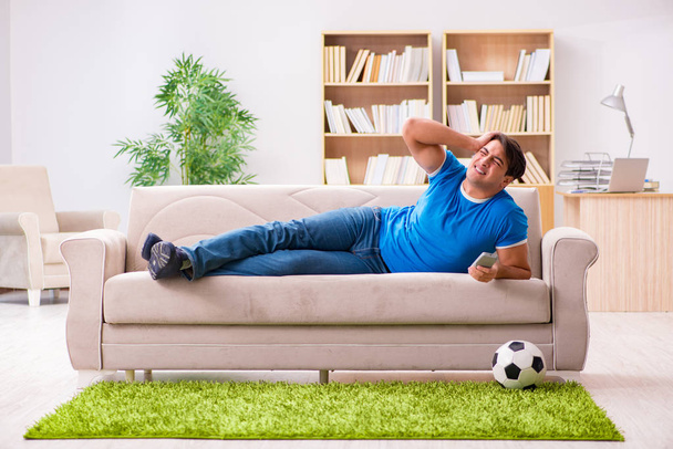 Hombre viendo fútbol en casa sentado en el sofá - Foto, imagen