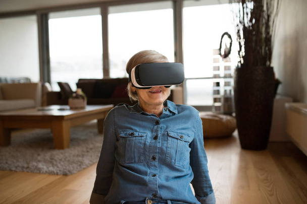 Senior woman wearing virtual reality goggles at home - Foto, immagini