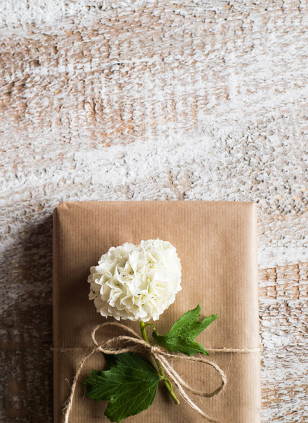 Present wrapped in brown paper, lilac flower laid on it. - Fotografie, Obrázek