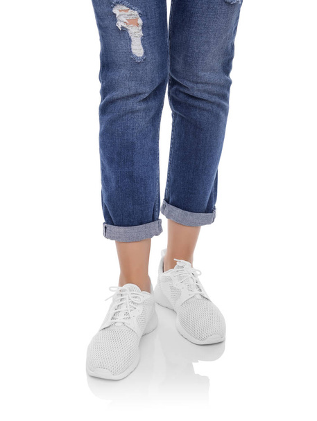 Womens legs in jeans and sneakers. - Foto, afbeelding