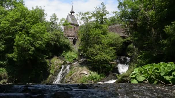 Cachoeira do rio Elz com pequena igreja em uma ponte e um velho moinho de água de meia madeira. O rio corre ao longo da aldeia Monreal e do castelo Burg Eltz. (Eifel, Alemanha
) - Filmagem, Vídeo