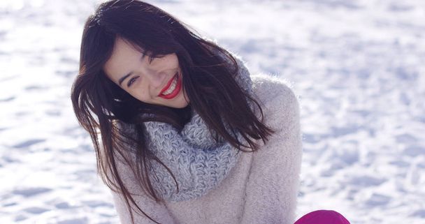 Sorrindo jovem mulher sentou-se na neve
 - Foto, Imagem
