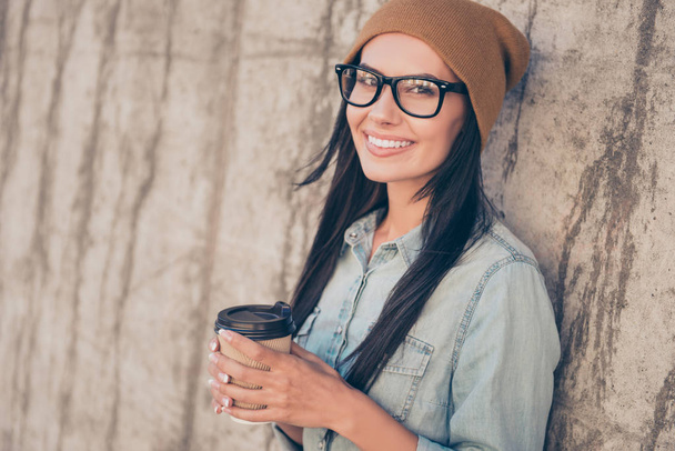 Happy girl in hat and glasses holding cup of tea on the backgrou - Photo, image