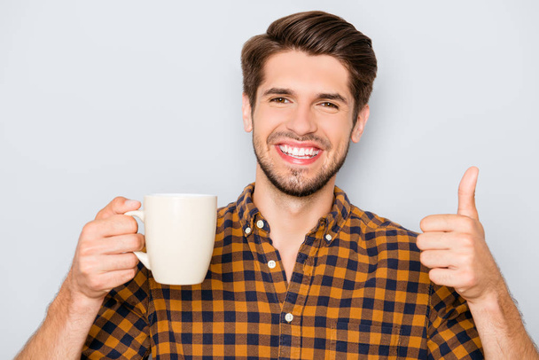 fröhlicher, fröhlicher Mann mit einer Tasse Tee gestikuliert wie - Foto, Bild