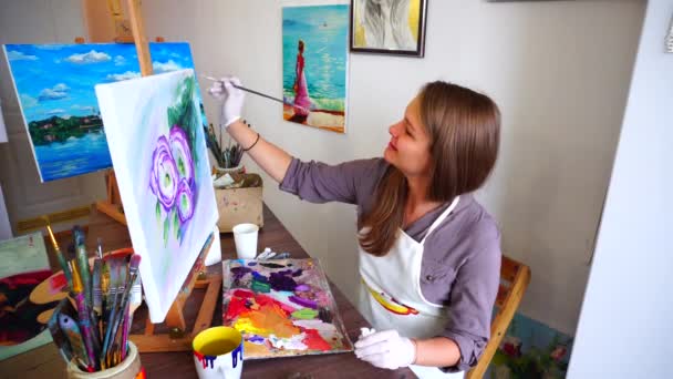 Γυναίκα ζωγράφος που κάνει τελευταία πινελιές να εγγραφής εικόνας και να κάθεται σε καρέκλα στο καβαλέτο Art Studio φως. - Πλάνα, βίντεο