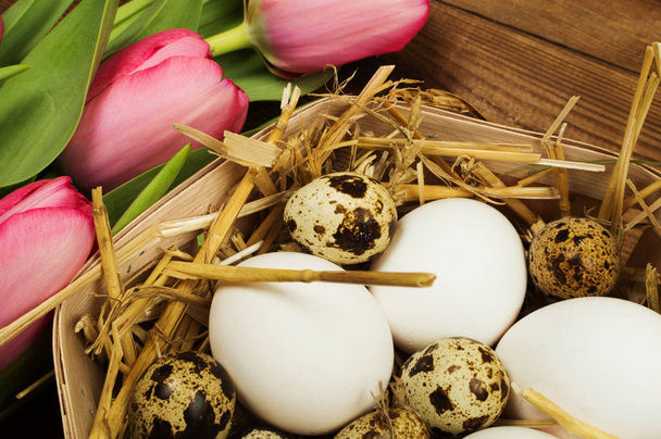 Chicken and quail eggs with tulips. Easter background - 写真・画像