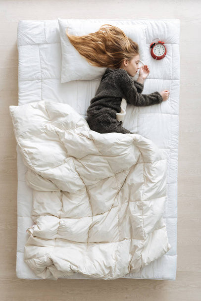 child sleeping next to clock - Photo, image