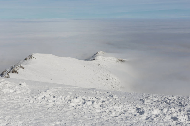 Snowy high mountains and clouds. View from the top of the mountain. - Фото, изображение