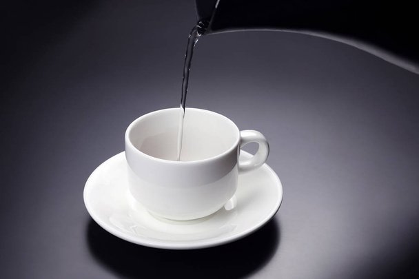 Wasser aus dem Wasserkocher wird in eine Tasse für Kaffee gegossen - Foto, Bild