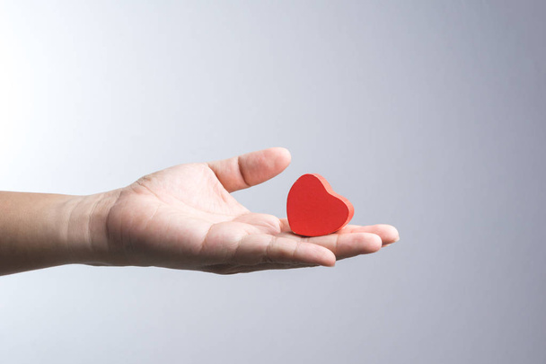 Une main d'homme avec un objet en bois rouge coeur
 - Photo, image