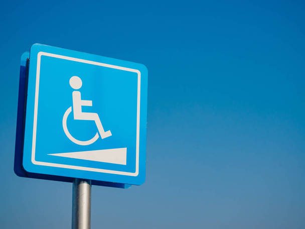 Места для парковки инвалидов и дорожные знаки инвалидных колясок и символы на столбе предупреждающие автомобилисты
 - Фото, изображение