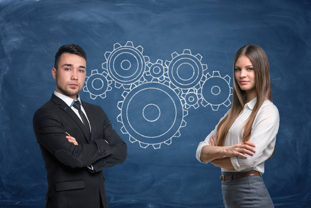 Businessman and businesswoman with gear wheels work in team on blue background - Фото, зображення