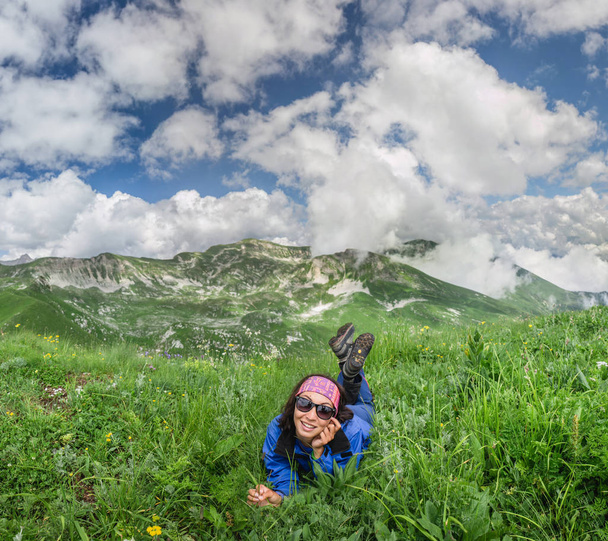 Donna è sdraiata e poggia sull'erba sulla cima della montagna
 - Foto, immagini