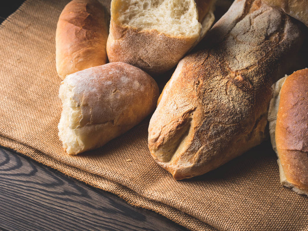 Versgebakken brood op jute donkere houten achtergrond - Foto, afbeelding