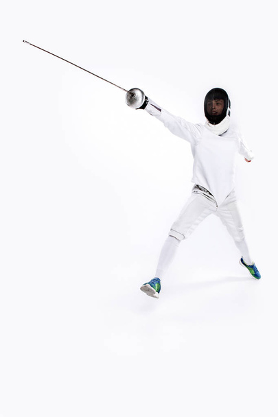 Man wearing fencing suit practicing with sword against gray - Fotoğraf, Görsel