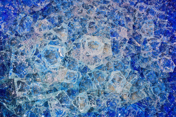 Блакитне розбите скло з бульбашками повітря. Візерунковий фон, що складається з жовтих кристалів та кераміки
. - Фото, зображення