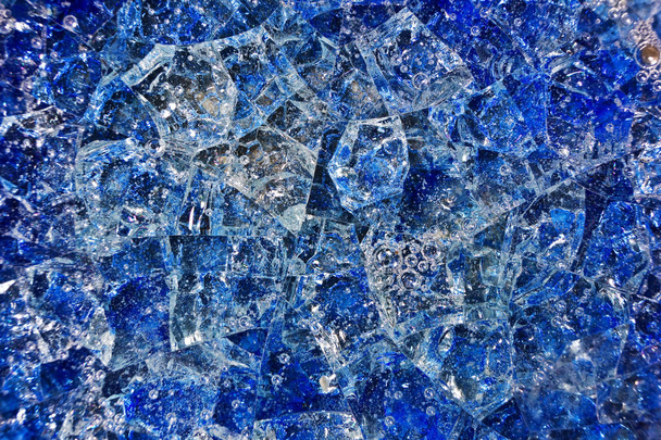 Блакитне розбите скло з бульбашками повітря. Візерунковий фон, що складається з жовтих кристалів та кераміки
. - Фото, зображення