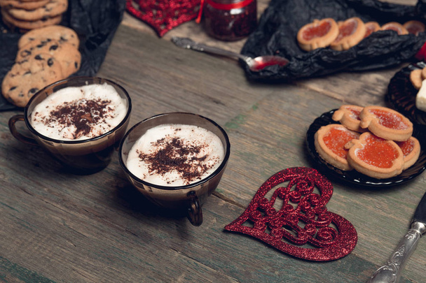 Petit déjeuner romantique. Deux tasses de café, cappuccino avec biscuits au chocolat et biscuits près des cœurs rouges sur fond de table en bois. Saint Valentin. L'amour. Vue du dessus
.  - Photo, image