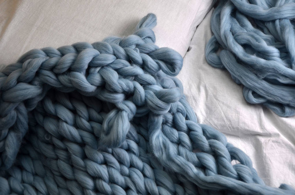 Composizione accogliente, primo piano plaid in lana merino a letto, atmosfera calda e confortevole. Sfondo maglia
 - Foto, immagini