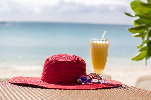Jugo fresco de naranja, sombrero y gafas de sol sobre el mar
 - Foto, Imagen