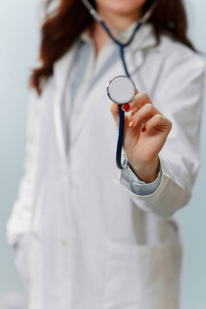 Kobieta lekarz na niebieskim tle przytrzymanie stetoskop ostrości - Zdjęcie, obraz