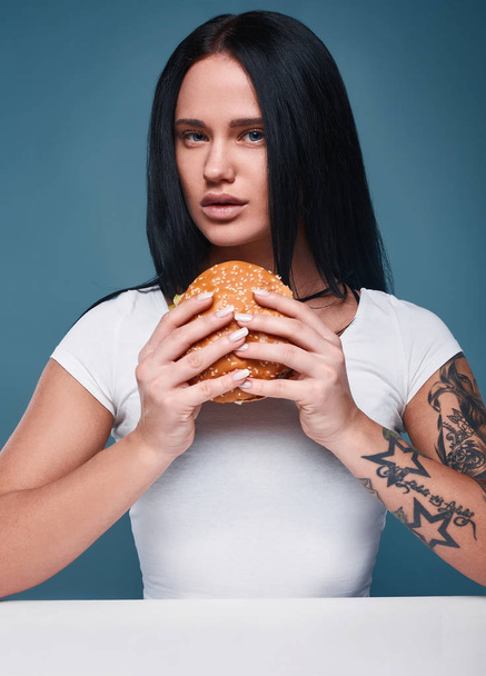 Beautiful charming tattoo girl holding hamburger - Valokuva, kuva