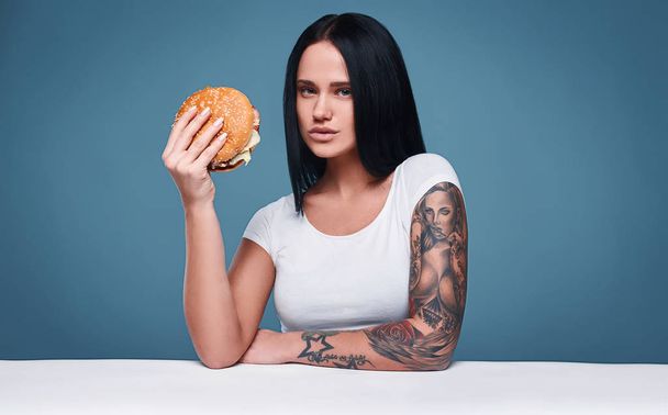 Gyönyörű bájos tetoválás girl gazdaság hamburger - Fotó, kép