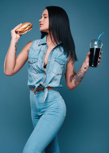 Beautiful charming tattoo girl with hamburger and soda - Zdjęcie, obraz