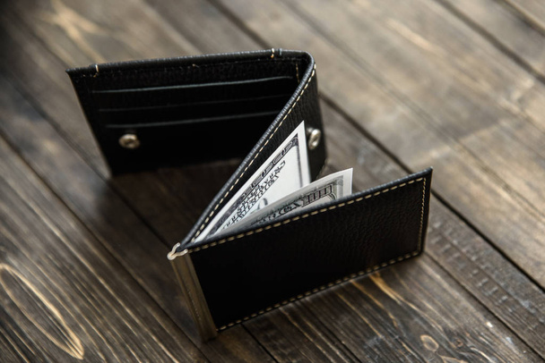 leather wallet on wood table with dollar bills - Fotó, kép