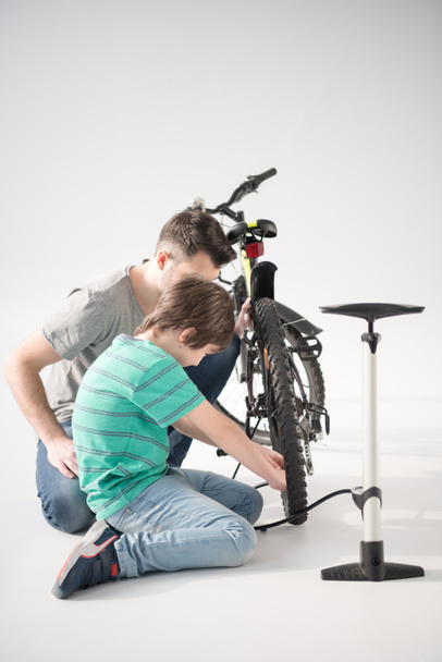 Pai e filho inflando pneu de bicicleta
 - Foto, Imagem