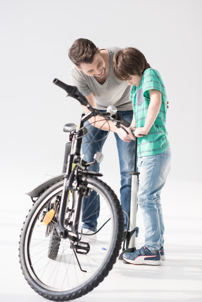 Отец и сын надувают велосипедную шину
 - Фото, изображение