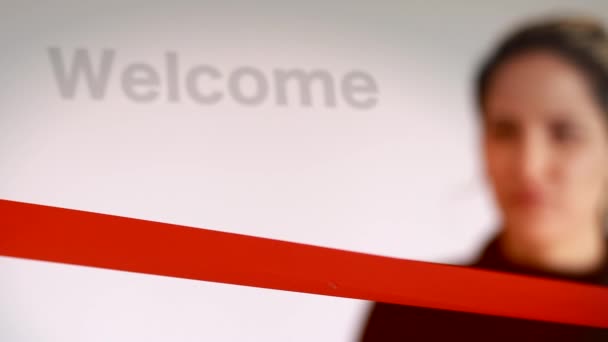 Shot of Woman cutting red ribbon with welcome sign - Footage, Video