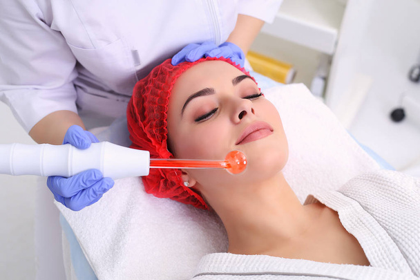 Receiving electric darsonval facial massage procedure. - Zdjęcie, obraz