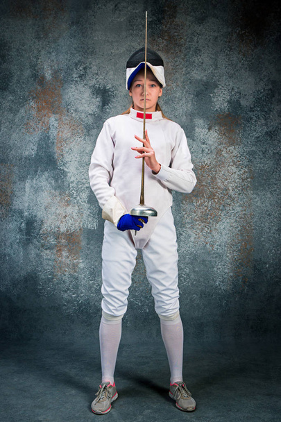 The woman wearing fencing suit with sword against gray - Foto, Bild