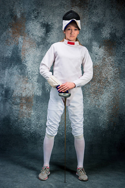 The woman wearing fencing suit with sword against gray - Fotoğraf, Görsel