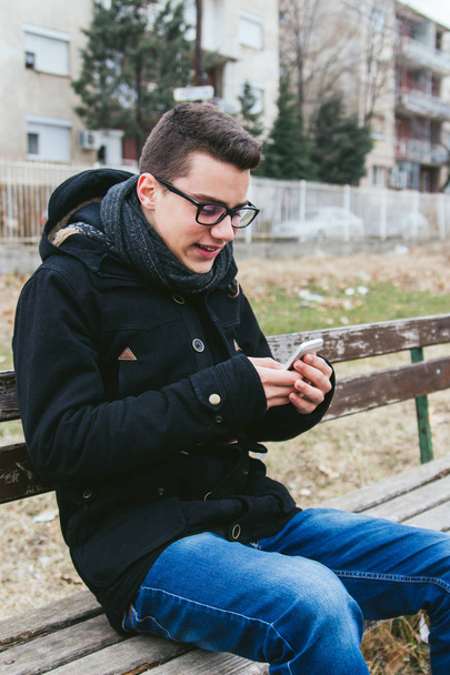Jeune homme utilisant un téléphone intelligent à l'extérieur
 - Photo, image